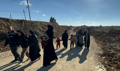 A group of women and children walk along a dirt road